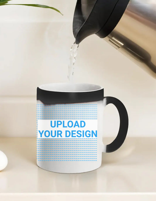 White mug with black handle being filled with water from a kettle on a light background